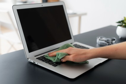 Person cleaning laptop to remove dust