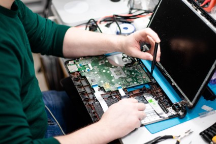 Technician repairing a laptop, providing professional help.